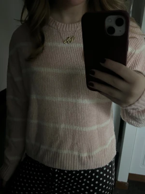 Ljusrosa randig stickad tröja H&M - Supermysig ljusrosa stickad tröja från H&M Divided i storlek XS. Tröjan har vita horisontella ränder, rund hals och ribbade muddar vid ärmslut och nederkant. Perfekt för dig som gillar en chill och söt stil.