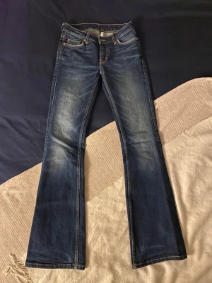 Weekday Flame Low Flared Jeans blå - SKIT SNYGGA blå jeans från Weekday, modell Flame Low Flared Jeans. De har låg midja och utsvängda ben med klassisk femficksdesign. Jeansen är tillverkade i jeansmaterial och har en cool tvätt med lätt slitning på låren och bakfickor. Älskar dessa så mycket!, men tvingas sälja då jag har växt ur dom🙏😔 Pris går att diskutera!