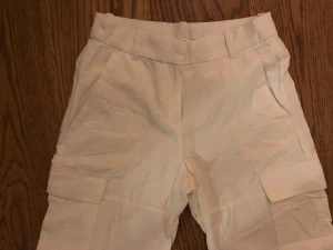 Vita cargobyxor stl 36 - Säljer ett par vita cargobyxor med fickor på sidorna. Materialet känns lätt och passar perfekt för en chill och avslappnad stil.