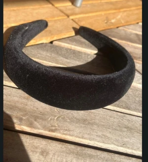 Svart puffigt sammetdiadem - Snyggt svart diadem med puffig form i mjuk sammet. Perfekt för att ge din look lite extra edge och passar lika bra till jeans som till klänning. Diademet är brett och ger en cool statement-känsla. Den har dock släppt i sömen den behöver ett eller två stygn