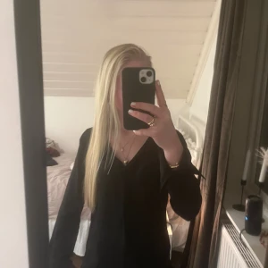 Svart v-ringad blus från Vila - Svart blus från Vila med v-ringad hals och långa ärmar. Enkel och stilren design med rak passform, perfekt för dig som gillar minimalistisk stil. Materialet känns mjukt och lätt mot huden. Snygg att matcha med smycken och boots. Den känns som satin, har knappar på ärmarna så den går att ha öppen eller vika upp 💞