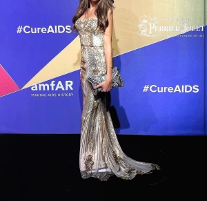 Glittrig långklänning i guld - Säljer en glittrig långklänning i guld med strapless design och figurnära passform. Klänningen har ett lyxigt mönster med paljetter och detaljer i guld och silver, samt en elegant släp. Perfekt för dig som vill sticka ut på bal eller fest.