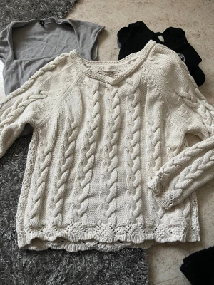 Vit stickad tröja med flätmönster - Superfin vit stickad tröja från Odd Molly med snygga flätor framtill och ett detaljerat mönster på ryggen. Tröjan har lång ärm, rund hals och är gjord i mjuk bomull. Perfekt för lager-på-lager och chill höst- och vinterstil.