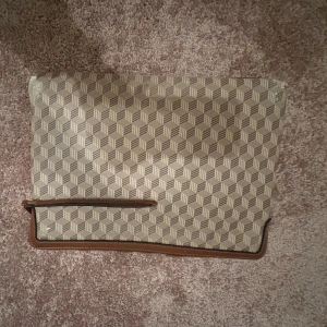 Datafodral  - Datafodral i brunt med geometriskt mönster. Den har detaljer i brunt skinn och dragkedja i guld. Den är väl använd och defekterna syns på bilderna. Men fortfarande fin🥰