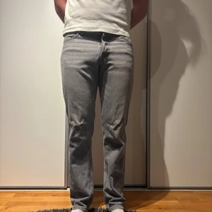 Grå Jack & Jones jeans straight fit - Säljer ett par grå jack & jones jeans med klassisk straight fit och fem fickor. Jeansen har knappgylf och är tillverkade i slitstarkt bomullsjeansmaterial. Perfekt för dig som gillar en tidlös look med lite loose passform och raka ben.