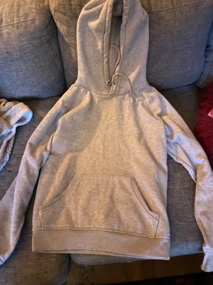 Grå hoodie från Bik Bok med huva - Mysig grå hoodie från Bik Bok i storlek S. Klassisk modell med stor känguruficka framtill, dragsko i huvan och ribbade muddar. Perfekt för chill dagar eller när du vill ha något bekvämt och stilrent. Materialet är mjukt och skönt mot huden.