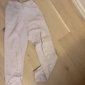 Ljusrosa mjukisbyxor med resår - Säljer ett par ljusrosa mjukisbyxor med elastisk midja och muddar vid bensluten. Perfekta för chill dagar och har en skön passform. Byxorna har snörning i midjan för extra komfort.