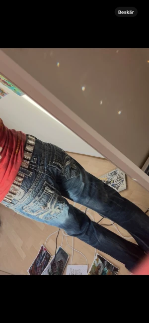Rock revival - Säljer ett par rock revival jeans med snygga broderade fickor och kontrastsömmar. Jeansen har en loose passform och coola slitningar, perfekt för dig som gillar streetstyle. Materialet är klassisk jeans och färgen är mörkblå med ljusare partier. Lol gpt vet sin grej asså