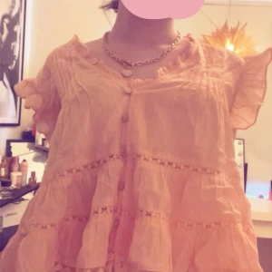 Ljusrosa volangklänning med knappar - Säljer en söt topp med volanger 🧸 fergen är beige/ lite orange aktig💕 super söt till sommaren !!