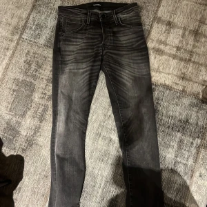 Svarta jeans från Jack & Jones Regular fit - Snygga svarta jeans från Jack & Jones med coolt tvättad look och klassiska fem fickor. Jeansen har normal passform och raka ben, perfekt för dig som gillar en stilren vibe. Materialet är slitstarkt denim och midjan är klassisk. Passar till sneakers eller boots. 