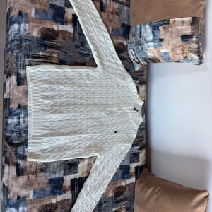 Vit kabelstickad kofta från Ralph Lauren - Snygg vit kabelstickad kofta från Ralph Lauren med dragkedja framtill och klassisk broderad logga på bröstet. Tröjan har långärmad design, ribbade muddar och är tillverkad i mjuk bomull. Perfekt för dig som gillar stilrena och tidlösa plagg.