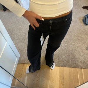 Svarta bootcut jeans med gråa detaljer - Säljer ett par svarta jeans med bootcut passform och cool grå jeans detaljer. Low waist och aldrig använda (prislapp kvar)