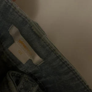 Blå bootcut jeans från Ginatricot - Snygga ljusblå jeans från Ginatricot i storlek 152. Modellen har bootcut-ben, slitningar på framsidan och klassiska fem fickor. Jeansen har knapp och dragkedja i midjan och är tillverkade i mjukt denimtyg. Har pyttesmå hål som jag sytt bra 