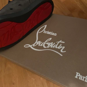 Grå mocka sneakers från Louboutin - Säljer ett par gråa sneakers från Christian Louboutin i mjuk mocka med klassisk röd sula. Skorna har rund tå, platt sula och snörning framtill. Snygg och stilren design som sticker ut med den ikoniska röda undersidan.