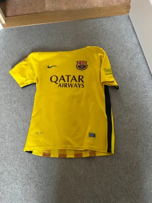 Barcelona Messi 10 gul matchtröja - Gul FC Barcelona fotbollströja från Nike med Messi 10-tryck på ryggen. Framsidan har Qatar Airways-logga och klubbmärke, baksidan har röda vertikala ränder och UNICEF-tryck. Kortärmad, tillverkad i lätt Dri-Fit material som andas. Perfekt för dig som älskar Barca och Messi.