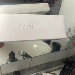 Apple Watch svart med extra armband - Apple Watch med svart fyrkantig urtavla och svart silikonarmband. I paketet ingår även ett vitt silikonarmband och laddare. Klockan har modern design och är perfekt för dig som gillar teknik och stilren look. Ny pris är ungefär vid 2000kr men den har varit använd under några tillfällen därför gör den ner i pris men annars nytt skicka!
