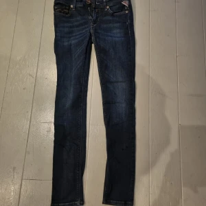 Replay jeans LUZ mörkblå skinny - Snygga mörkblå jeans från Replay i storlek W28 L30, modell LUZ. Skinny fit med klassisk femficksdesign och coola detaljer på bakfickorna. Jeansen har gul kontrastsöm och läderpatch med Replay-logga bak i midjan. Perfekt passform och stilren look.
