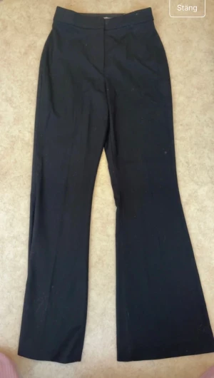 Svarta bootcut kostymbyxor H&M - Snygga svarta kostymbyxor från H&M i storlek 34. Byxorna har bootcut-ben och hög midja som ger en clean och stilren look. Perfekta för dig som gillar klassisk och trendig look.