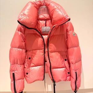Rosa Moncler pufferjacka  - Säljer en rosa pufferjacka från Moncler hög krage och Moncler-märke på ärmen. Jackan har dragkedja framtill, två fickor med knappar och quiltad design. Materialet är glansigt och känns lyxigt✨💞Passar en xs/s. Skriv privat för fler bilder! 