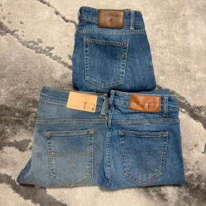 Dondup jeans  - Tre par blå  jeans, två från T/J och ett från Dondup. Alla har klassisk femficksdesign, skinnpatch bak i midjan och smal passform. Jeansen är i olika blå tvättar, från ljus till mellanblå, och har snygga slitningar och detaljer. Perfekta för en avslappnad och trendig look. Dondup: l30 w: 28/29 T/G: w29 l30 båda