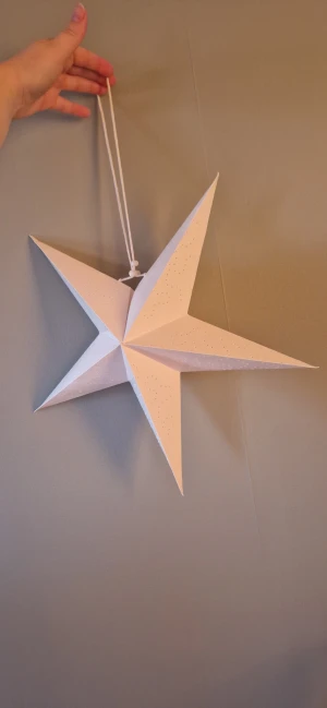 Vit adventsstjärna med hålmönster - Fin vit adventsstjärna i papper med dekorativa hålmönster. Perfekt för fönsterdekoration. Några mindre skador och lagningar syns på spetsarna men inget som syns tydligt- i övrigt gott skick. 