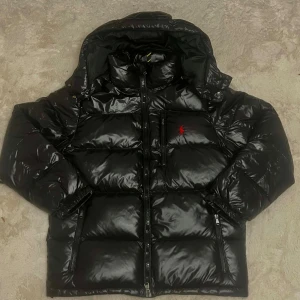 Ralph Lauren Jacka - ✨ Färg: Svart (glansig finish) 📏 Storlek: S 💯 Skick: Felfri i toppskick! 💎 Supersnygg blank vinterjacka med den röda Polo-loggan. ☃️ Varm, lätt och passar perfekt både till vardags och citystil.