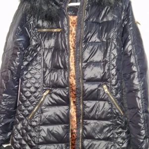 Svart dunjacka Rockandblue med päls - Svart dunjacka från Rockandblue med fluffig svart fuskpäls på huvan och leopardmönstrat foder. Jackan har guldfärgade dragkedjor, quiltad design och flera fickor. Perfekt för dig som vill ha en snygg och varm jacka med coola detaljer.