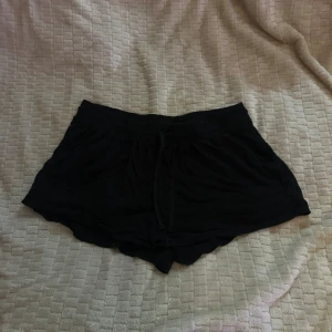 Svarta shorts med snörning - Svarta, lösa shorts med snörning i midjan. De har en mjuk och flowy känsla, perfekt för varma dagar. Shortsen har en enkel design och är riktigt bekväma att bära.