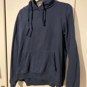 Mörkblå hoodie från OTP Leisurewear XL - Mörkblå hoodie från OTP Leisurewear i storlek XL. Tröjan har huva med snörning, stor magficka och ribbade muddar vid ärmslut och nederkant. Tillverkad i mjuk bomull, perfekt för chill dagar. Klassisk och enkel design utan mönster.