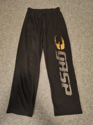 GASP byxor  - Svarta mjukisbyxor från GASP i storlek M med bred passform och snörning i midjan. Materialet är i mesh vilket gör de luftiga o sköna. Perfekta för chill eller gymmet. Nypris: 599