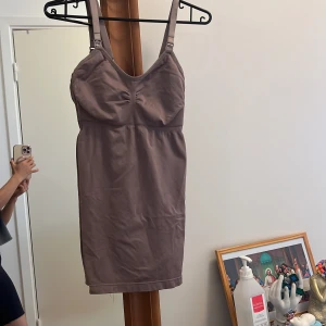 Mauve kort klänning med smala axelband - Säljer en enkel och stilren kort klänning i mauve med smala justerbara axelband och lätt rynk vid bysten. Klänningen har en kroppsnära passform och är perfekt för varma dagar. Materialet känns mjukt och stretchigt, vilket gör den bekväm att bära.