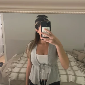 Grå bolerotopp med knyt i midjan - Supersöt grå bolerotopp från Gina Tricot med korta ärmar och knyt i midjan. Tunt och mjukt bomullsmaterial som ger en avslappnad vibe. Perfekt att slänga över ett linne eller bandeau. Säljer då den inte kommer till användning längre!