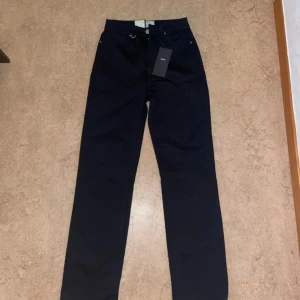 Svarta NEUW Nico jeans straight - Svarta jeans från NEUW, modell Nico, med rak passform och klassisk femficksdesign. Byxorna har hög midja och dragkedja framtill. Tillverkade i bomull med stretch för extra komfort. Snygga och stilrena jeans som passar till det mesta.