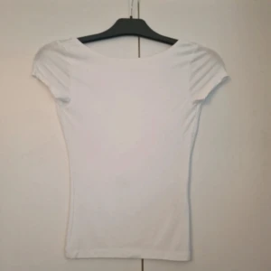 Vit topp - ‼️PRISET ÄR INTE HUGGET I STEN‼️Säljer en vit, tight topp från Gina Tricot i storlek XS. Toppen har korta ärmar och en djup, rundad rygg. Enkel och stilren design som sitter figurnära och är gjord i mjukt bomullsmaterial.