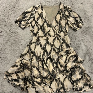 Beige och svart omlottklänning från ONLY - 🤎En superfin klänning från Only 🤎I beige, brun och svart  🤎Volanger i kjolen, V ringning 🤎Storlek M 🤎Använd endast en gång!.