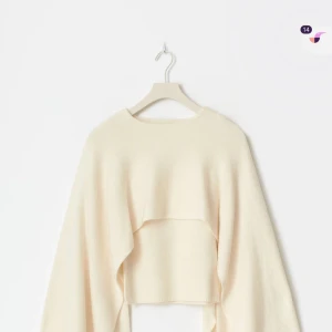 Beige croppad stickad tröja med cape - Säljer en krämvit stickad tröja med unik cape-liknande design och långa ärmar från Gina tricot. Tröjan har en rund halsringning och är gjord i mjukt stickat material som ger en cool och modern siluett. Använd en gång och slutsåld på hemsidan. De är stolen L men skulle själv säga att den är som en M