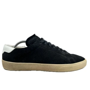 Svarta Saint Laurent sneakers mocka - Svarta sneakers från Saint Laurent i mjuk mocka med beige platt gummisula och vit detalj på hälen. Klassisk låg modell med rund tå och snörning framtill. Perfekt för dig som gillar stilrena och lyxiga skor med minimalistisk vibe. Pris kan diskuteras privat!