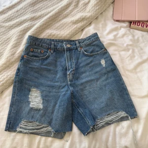 Blå jeansshorts med slitningar från H&M - Säljer ett par blå jeansshorts med slitna detaljer framtill. 