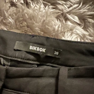 Svarta kostymbyxor från Bik Bok - Populära kosrymbyxor från Bikbok med slits, storlek 38 men lite små i storleken