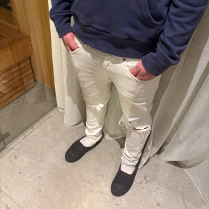 Dondup jeans - Säljer ett par vita jeans med skinny passform och slitna detaljer vid knäna. Byxorna har klassiska fem fickor. Materialet är jeans och de har en modern.