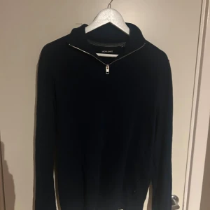 Mörkblå half zip tröja Jack & Jones - Mörkblå långärmad tröja från Jack & Jones med stilren half zip-dragkedja vid halsen. Tröjan är stickad och har en klassisk passform som funkar till många olika looks. Perfekt för dig som gillar enkel och clean stil.