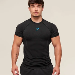 Gymshark Onyx 5 Black/Onyx Grey - Svart t-shirt från Gymshark med blå logga på bröstet. Modellen är tight och har korta ärmar samt sportig meshstruktur upptill. Perfekt för dig som gillar att träna och vill ha en snygg och funktionell look.