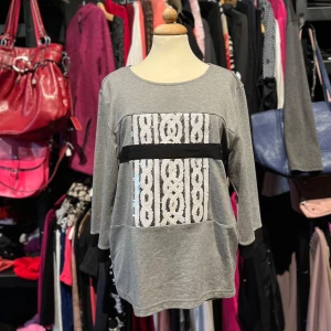 Grå tröja med paljettdetalj från Luxzuz - Grå långärmad tröja från Luxzuz med svart kant vid ärmslut och en bred svart rand över bröstet. Framsidan har ett mönster av vita paljetter som ger cool effekt. Tröjan är i mjuk viskosmix med polyester och elastan för extra komfort.