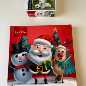 Favorina Julpussel & Trefl Mini Puzzle Hund - Två roliga pussel! Ett julpussel med tomte, snögubbe och ren i färgglad design, perfekt för vintermys 56 bitar och mäter 19x19 cm. Det andra är ett mini-pussel med en söt vit hund och fotboll, 54 bitar, 20x13 cm. Passar dig som gillar djur och julstämning!