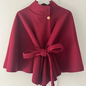 Vinröd kappa med bälte från Missay - Fantastiskt fin vinröd kappa från Missay, den är lite mörkare i färgen än vad bilden visar! Kappan har ett knytband i midjan som är avtagbar. Denna kappan är perfekt för dig som vill sticka ut med en elegant look under höst och vinter✨