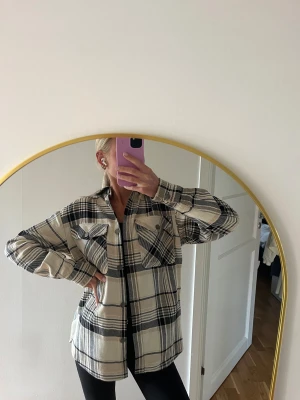 Beige & svart rutig overshirt - Säljer en oversized overshirt i beige & svart med rutigt mönster. Jackan har två stora bröstfickor med knappar, klassisk krage och långa ärmar. Säljer då den tyvärr inte kommer till användning längre. Den är i mycket fint skick! Storlek XS🤎
