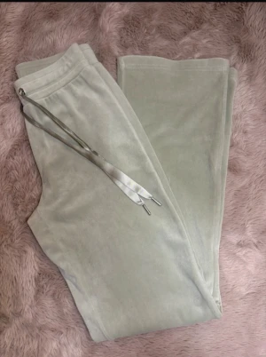 Ljusgröna mjukisbyxor med snörning Young Gina stl.XXS - Snygga ljusgröna mjukisbyxor i mjukt och lent material med bred resår i midjan och blanka snören framtill. Byxorna har raka ben och är perfekta för en chill och avslappnad stil. Materialet är 95% polyester och 5% elastan för extra stretch och komfort.