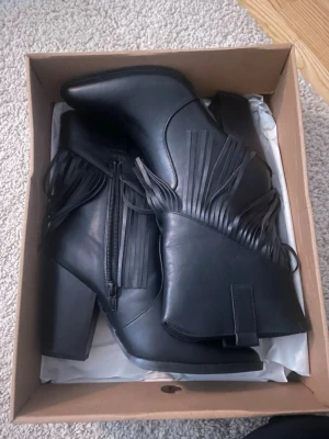Svarta boots med fransar och klack - Snygga svarta boots med fransar, perfekta till tema fester men också i vardagen till jeans. Helt oanvända köpte från zalando några år tillbaka. Kan tänka mig gå ner i pris vid snabb affär💕
