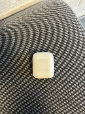 Apple AirPods (2nd generation) äkta! - Apple AirPods med laddningsetui. Trådlösa hörlurar med enkel anslutning till iPhone och andra Apple-enheter. Etuiet visar tydligt yttre slitage och smuts, men fungerar som det ska. Perfekt för dig som vill ha smidig musik och samtal utan sladdar.