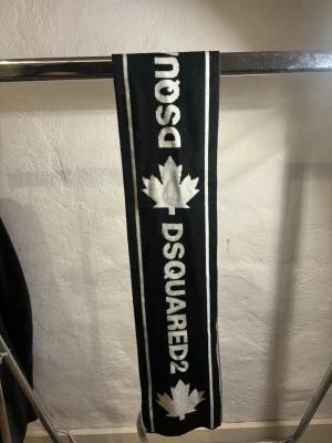  Dsquared2 - halsduk - Snygg halsduk från Dsquared2 i svart och vitt med tydlig logga och lönnlövsmotiv. Stickad i mjukt material som håller dig varm och ger en cool vibe till din outfit. Nytt skick✅ , ny pris 1500, mitt pris 99kr. Hör av dig vid funderingar 📩